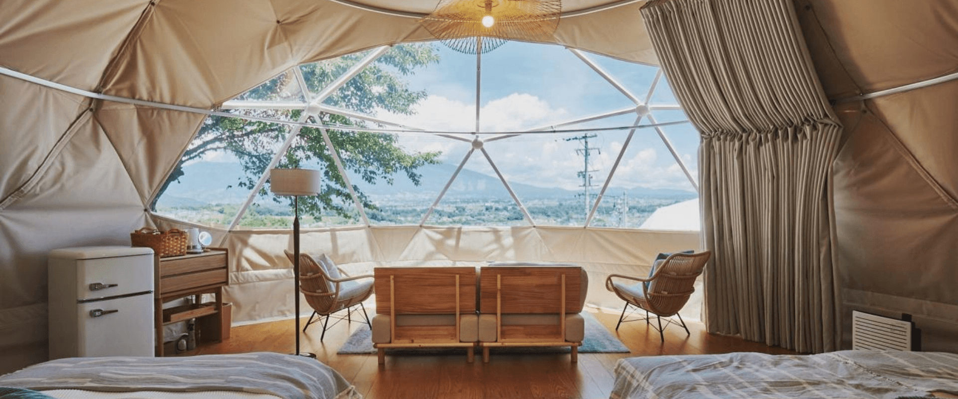 窓に向かって2脚の椅子が置かれたグランピングドームの内装